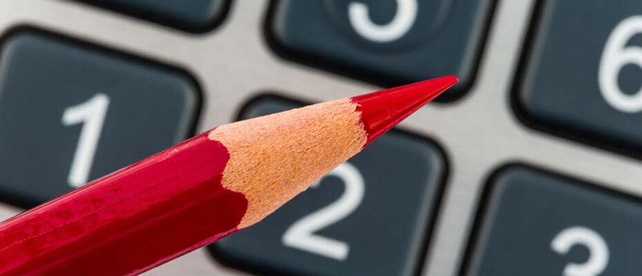 Ein roter Stift liegt auf einem Taschenrechner. Sparen bei Kosten, Ausgaben und Budget wegen schlechter Konjunktur | © Gina Sanders - Fotolia
